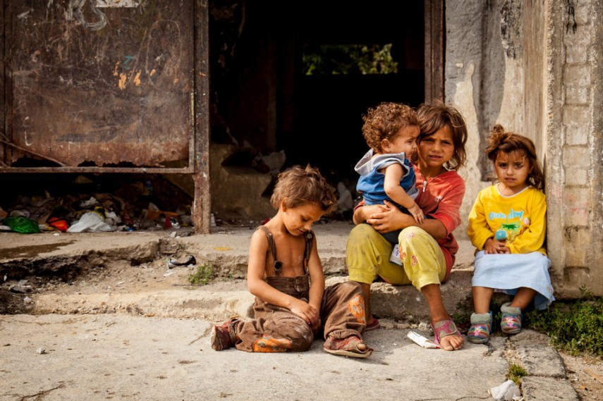 Foto de diversas crianças sentadas na calçada. Suas roupas surradas e o local indicam que são pobres