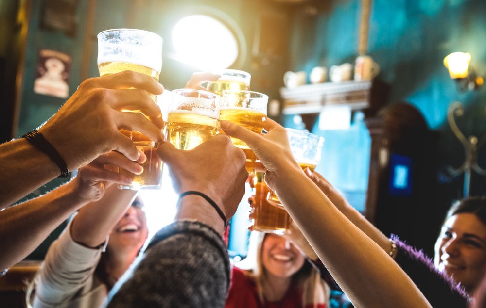 Foto de diversas pessoas brindando com cerveja