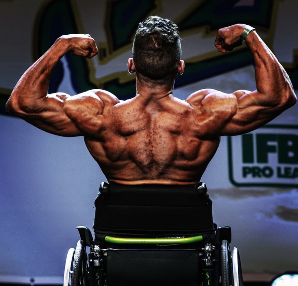 foto de um cadeirante bodybuilder de costas, flexionando seus músculos.